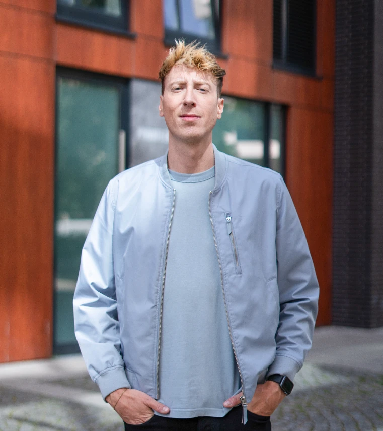 Marc Engelmann in hellblauer Jacke vor einem Gebäude in Hamburg